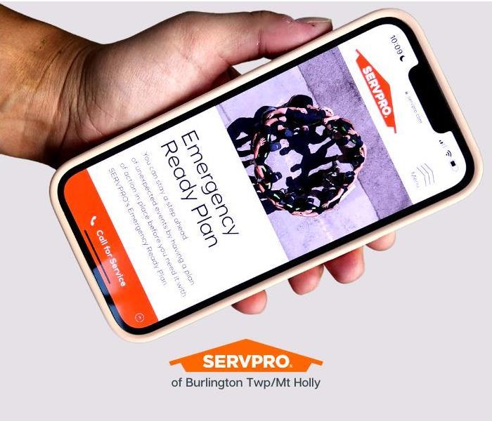 Hand holding an iPhone with SERVPRO website up with Emergency Ready Plan